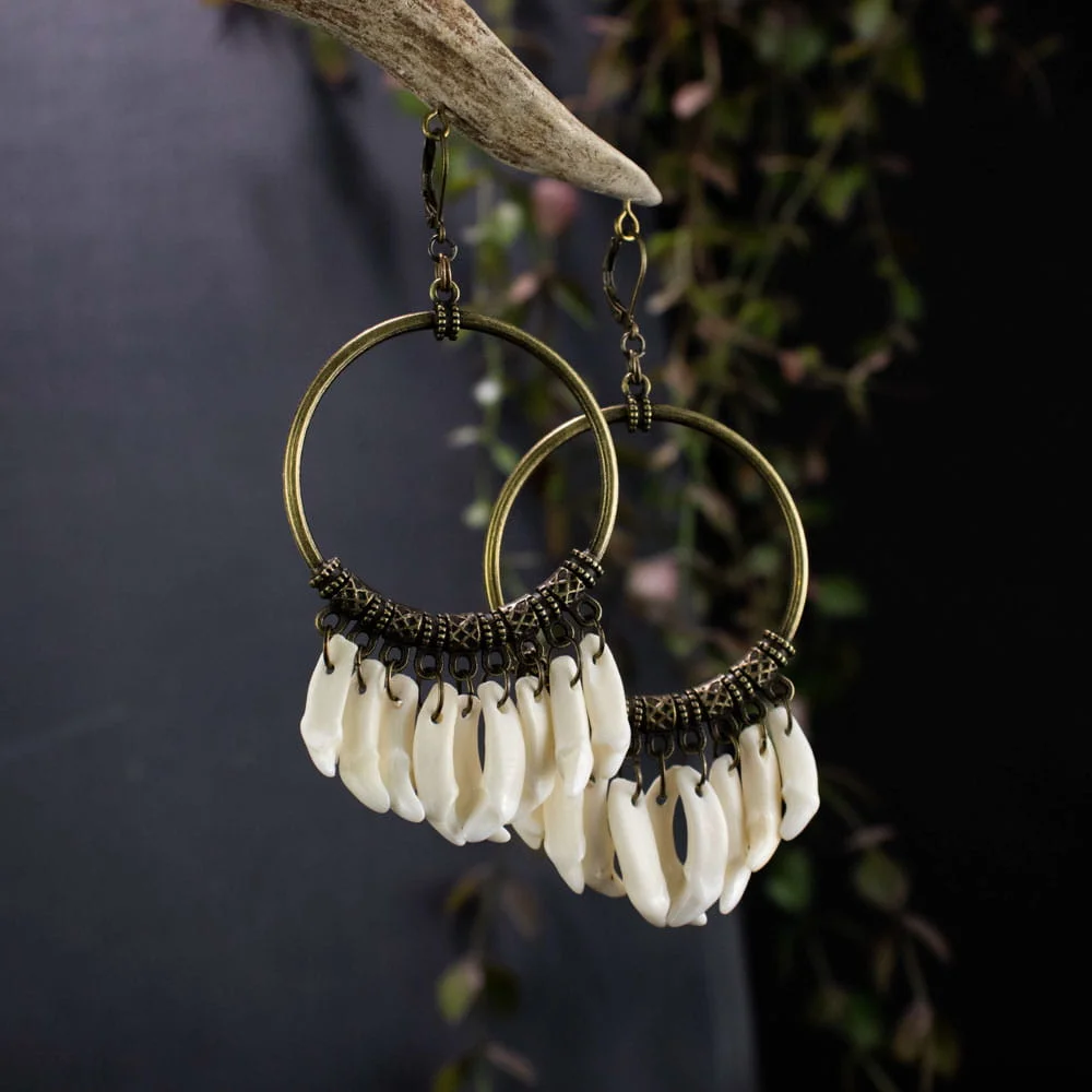 Detailed shot of authentic mink fangs and textured bronze charms, showcasing the raw materials of these boho bone jewelry.