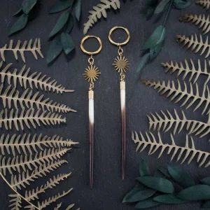 Gold leverback hoop earrings with natural quills and gold star charms, displayed on a dark, mystical surface with subtle shadows.