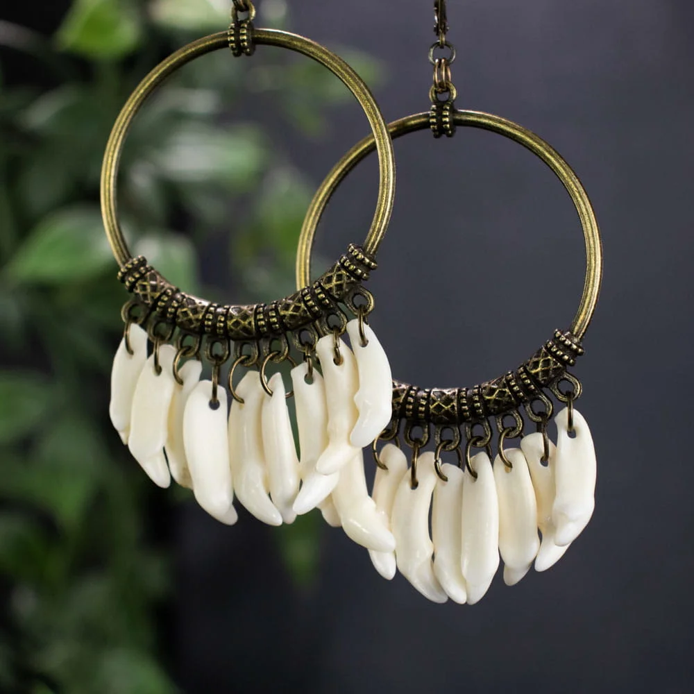 Woman wearing real bone earrings with mink fangs and bronze dangles, highlighting the naturalistic and folk aesthetic.