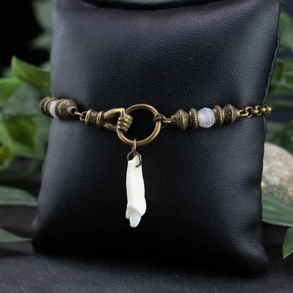 Macro shot of the oxidized bronze chain links connecting the fox teeth and smooth white agate beads, highlighting the ritualistic artisan detail.
