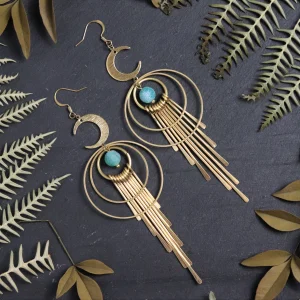 Handcrafted witchy hoop earrings with golden starburst charms and celestial elements, displayed on a dark, textured surface.