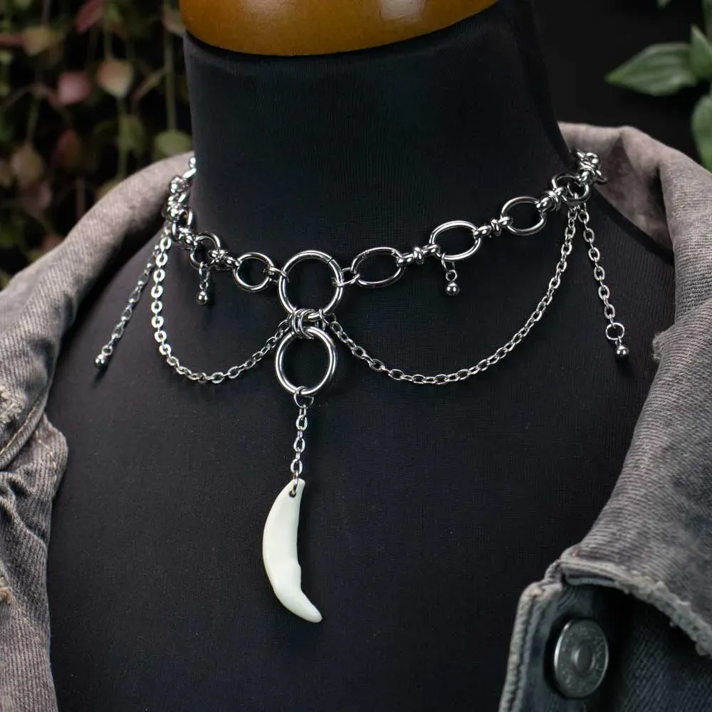 The cascading fang necklace, set on a dark natural surface for an edgy, alternative gift presentation.