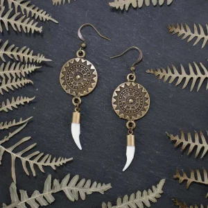 Detailed shot of authentic mink fangs and textured bronze charms, showcasing the raw materials of these boho bone jewelry.