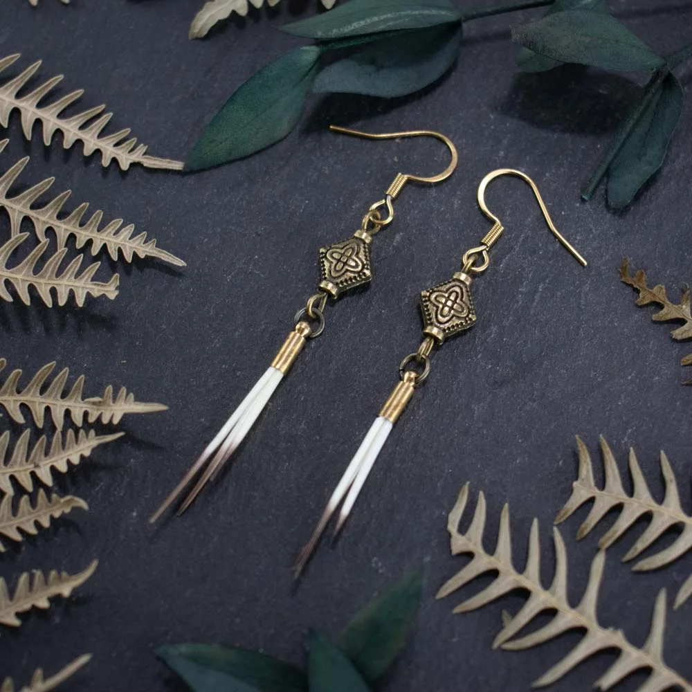 Detailed shot of small natural quills clustered within a rustic bronze ethnic end cap.