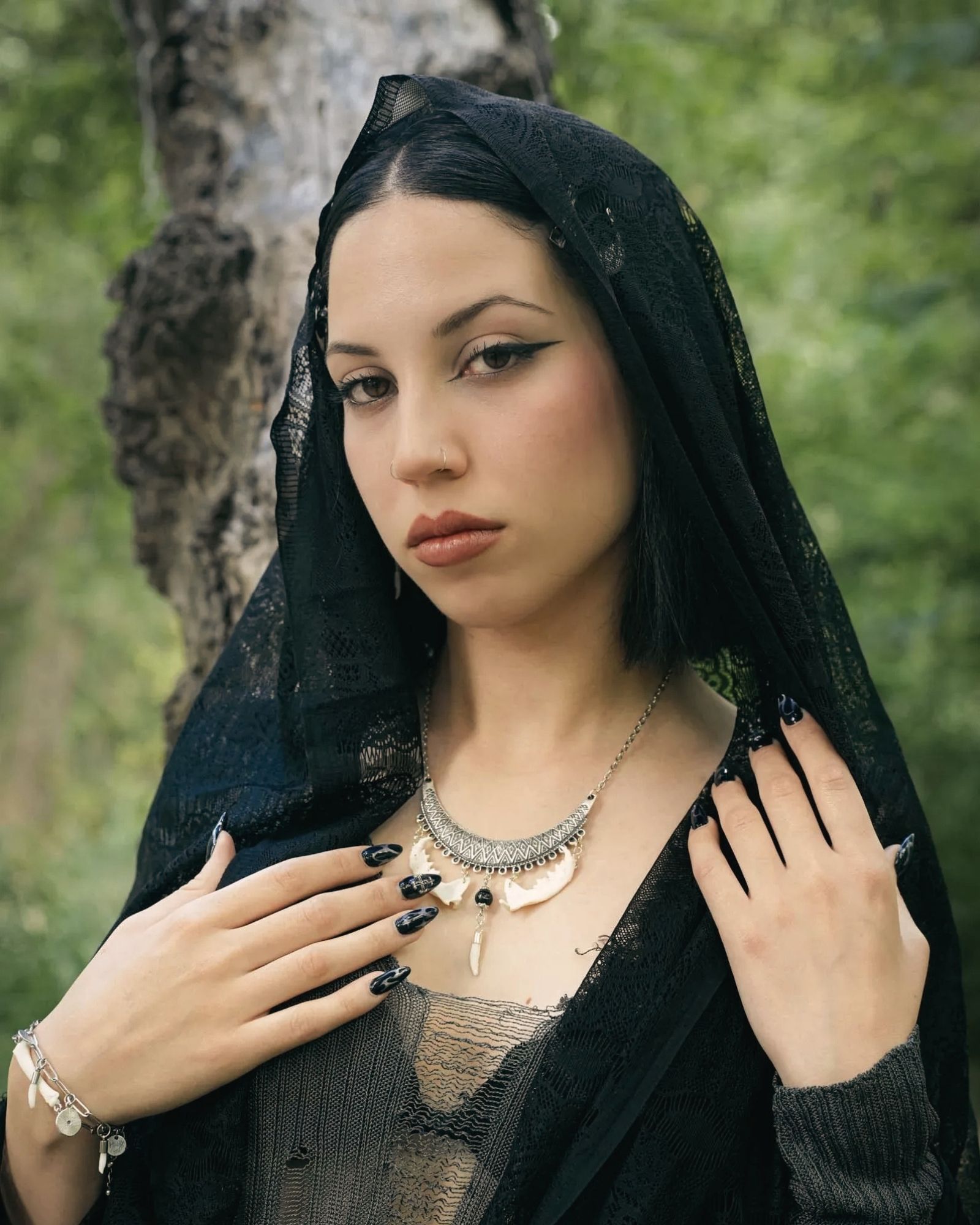 Goth girl wearing silver necklace with real mink fangs.